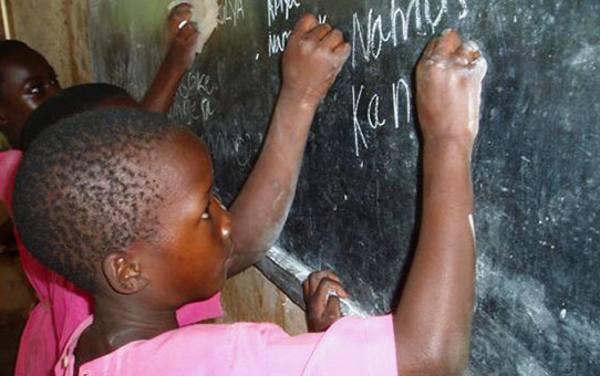 School children practise writing on a blackboard